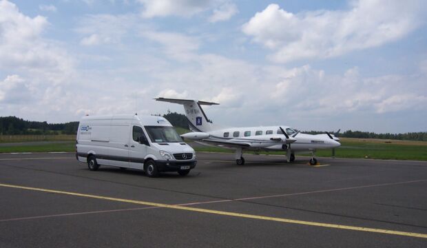 Luftfracht Anlieferung per Kleintransporter am Rollfeld neben einem Kleinflugzeug für Aircharter.