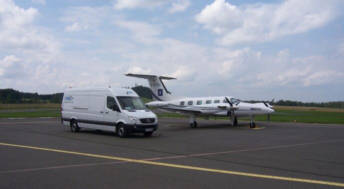 Mercedes-Benz Sprinter van parked on the tarmac next to a small aircraft for air charter